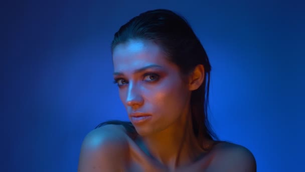 Glühendes Mode-Model in blauem Neonlicht zeigt sich von allen Seiten in die Kamera. — Stockvideo