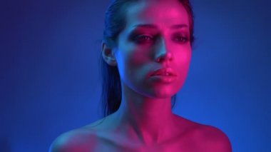 Mavi ve pembe neon ışıklar glitter makyaj ile parlayan moda yıldızı düşünceli kamera içine izlerken.