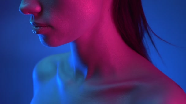 파란색과 분홍색 네온 불빛에 서있는 움직이지 않는 빛나는 모델의 프로필에서 클로즈업 촬영. — 비디오