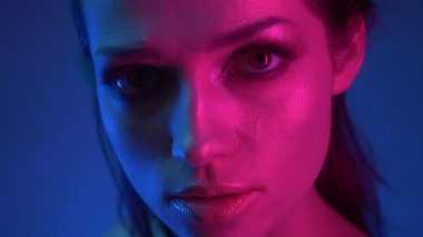 Mavi ve pembe neon ışıklar moda modeli nin yakın çekim kamera gözlerini yükseltir ve içine konsantrasyon ile izlerken.