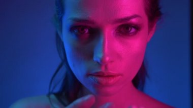 Mavi ve pembe neon ışıklı model profilinde yakın çekim kamera içine dikkatle uzanarak izliyor.