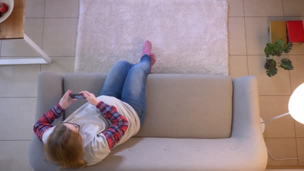 Primo piano top shoot di giovane femmina incinta scattare selfie al telefono mentre seduto sul divano in casa — Video Stock