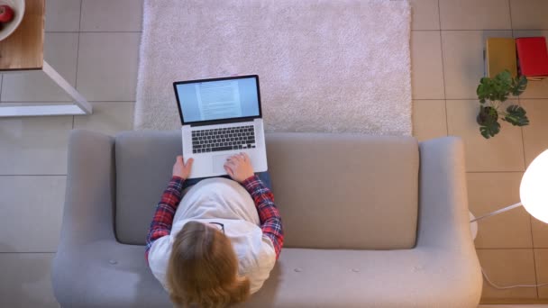 Closeup top shoot of young pregnant female using the laptop while sitting on the couch indoors — Stock Video