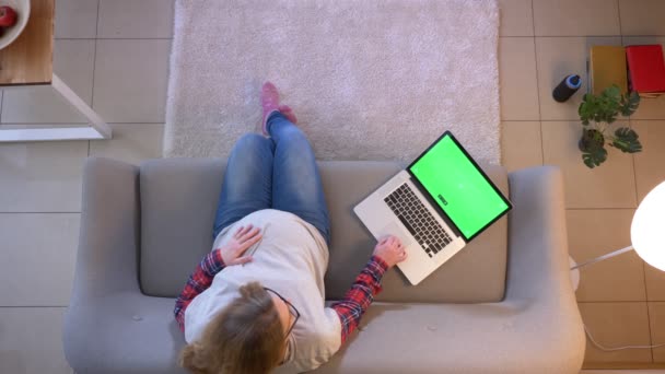 Tiro superior close-up de jovens mulheres grávidas navegando no laptop com tela verde enquanto sentado no sofá dentro de casa — Vídeo de Stock