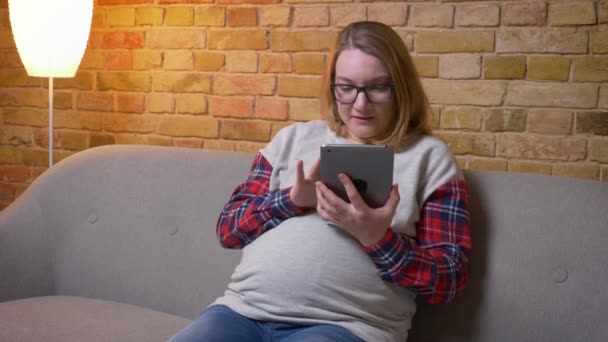 Střílejí mladé těhotné samice za použití tabletu, zobrazující zelenou obrazovku fotoaparátu, zatímco sedíte na pohovce v útulném bytě uvnitř — Stock video