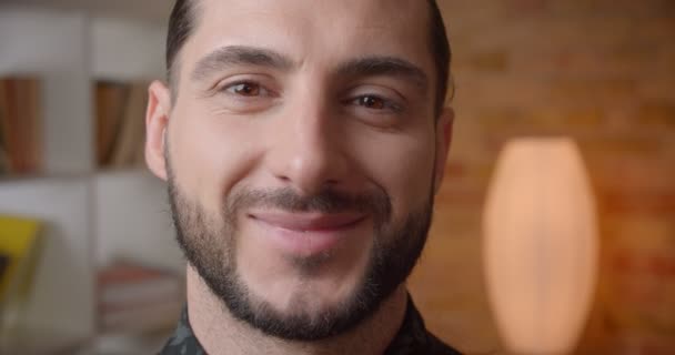 Närbild shoot av unga attraktiva muslimska skäggiga manliga ansikte tittar på kamera med leende ansiktsuttryck inomhus — Stockvideo