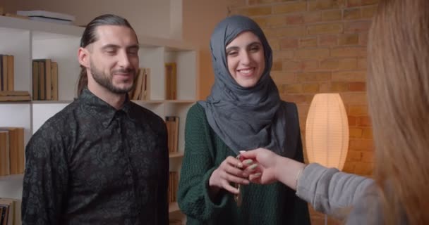 Nahaufnahme Shooting junger attraktiver muslimischer Coulpe, die eine Wohnung kauft, Hände schüttelt und glücklich umarmt — Stockvideo