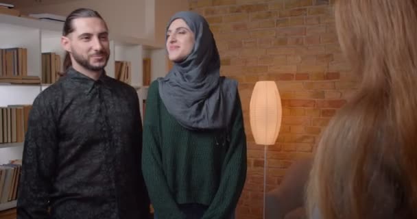 Nahaufnahme Shooting junger attraktiver muslimischer Coulpe, die eine Wohnung kauft, Schlüssel von Umbauunternehmen erhält und sich glücklich umarmt — Stockvideo