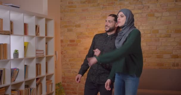 Nahaufnahme eines jungen attraktiven arabischen Paares, das sich in einer neu gekauften Wohnung im Haus niederlässt — Stockvideo