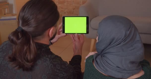 Kapalı alanda uygulama ile yeşil ekran ile tablet kullanarak genç neşeli Müslüman çift Closeup geri görünümü ateş — Stok video