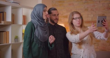 Yeni satın alınan bir dairede neşeyle kapalı sarılma bir tablet ile realter konuşurken genç mutlu Müslüman çift Closeup ateş..