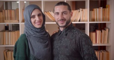 Genç mutlu müslüman çift in closeup ateş kamera düz bakarak ve yeni satın alınan bir dairede neşeyle gülümseyerek