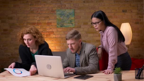 Closeup hajtás fiatal üzletember dolgozik a laptop egyre boldog és ünneplő sikert két női kollégák. Írótábla tartó üzletasszony — Stock videók
