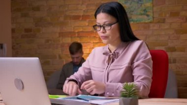 Dizüstü bilgisayar üzerinde çalışan ve kanepede oturan ve arka planda tablet kullanarak işadamı için grafik işleme yetişkin Asya lı iş kadını Closeup ateş