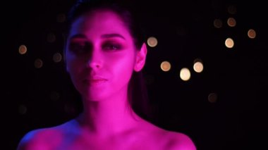 Pembe neon ışık ve bokeh arka plan baştan çıkarıcı kameraya bakarak genç çarpıcı kafkas kadın Closeup ateş