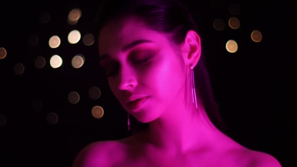 Close-up tiro de jovem mulher branca deslumbrante com luz de néon rosa e fundo bokeh — Vídeo de Stock