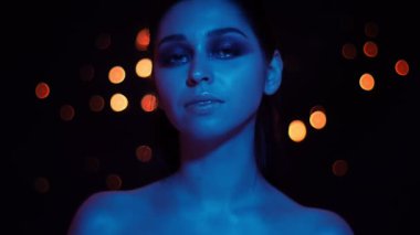 Kamera bakarak mavi neon ışık ve bokeh arka plan ile genç güzel kafkas kadın Closeup ateş
