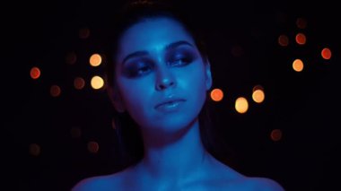 Kamera önünde poz mavi neon ışık ve bokeh arka plan ile çarpıcı makyaj ile genç güzel kafkas kadın Closeup ateş