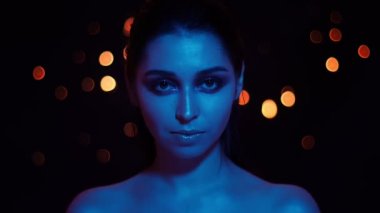 Kamera bakarak mavi neon ışık ve bokeh arka plan ile çarpıcı makyaj ile genç güzel kafkas kadın Closeup ateş