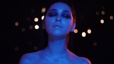 Mavi ve kırmızı neon ışık ve bokeh arka plan kamera bakarak çıplak omuzlu genç güzel kafkas kadın Closeup ateş