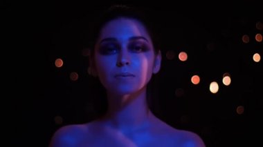 Mavi ve kırmızı neon ışık ve bokeh arka plan kamera bakarak glitter makyaj ile genç güzel kafkas kadın Closeup ateş