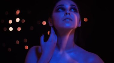 Mavi neon ışık ve bokeh arka plan kamera bakarak glitter makyaj ile genç güzel kafkas kadın Closeup ateş