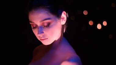 Kamera önünde poz pembe ve sarı neon ışık ve bokeh arka plan ile çarpıcı glitter makyaj ile genç güzel kafkas kadın Closeup ateş