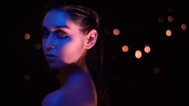 Kamera önünde poz pembe ve sarı neon ışık ve bokeh arka plan ile çarpıcı glitter makyaj ile güzel kadın Closeup ateş