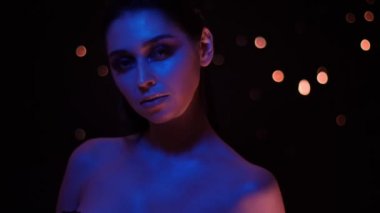 Mor neon ışık ve bokeh arka plan kamera önünde poz ile glitter makyaj ile güzel kadın Closeup ateş