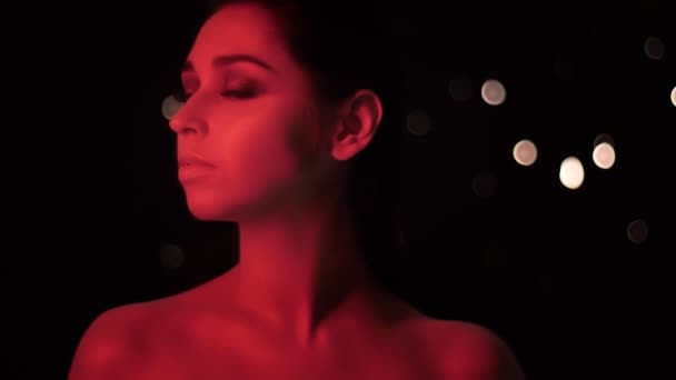 Kamera önünde poz kırmızı neon ışık ve bokeh arka plan ile çarpıcı makyaj ile güzel kadın Closeup ateş — Stok video
