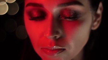 Kamera önünde poz kırmızı neon ışık ve bokeh arka plan ile çarpıcı makyaj ile güzel kadın yüz Closeup ateş