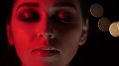Kırmızı neon ışık ve bokeh arka plan baştan çıkarıcı gülümseyen çarpıcı makyaj ile güzel kadın yüz Closeup ateş