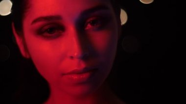 Gece kulübünde kamera önünde poz kırmızı neon ışık ve bokeh arka plan ile çarpıcı vogue makyaj ile güzel kadın yüz Closeup ateş