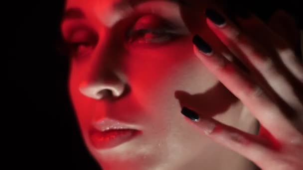 Κοντινό γύρισμα του όμορφο θηλυκό πρόσωπο με εκπληκτική μακιγιάζ με κόκκινο φως νέον και bokeh φόντο — Αρχείο Βίντεο