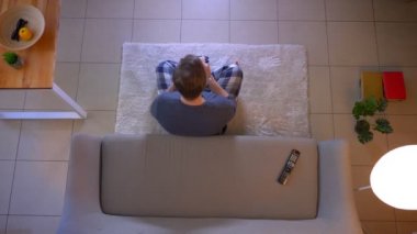 Genç rahat giyimli erkek Closeup üst ateş kanepede oturan Tv izlerken ve rahat evde kapalı tarifi yazma