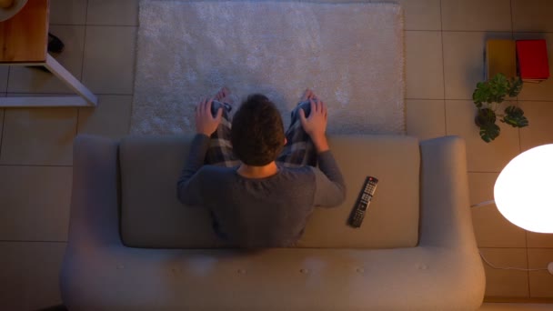 Hlavní střelce mladého muže, který sleduje fotbalové utkání v televizi, jak se šťastně a vzrušuje doma v útulném domě s večerními světly — Stock video