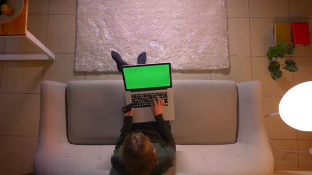 Närbild topp shoot av unga ganska kvinnlig shopping online med kreditkort med hjälp av den bärbara datorn med grön skärm medan du sitter på soffan inomhus på Cozy Home — Stockvideo
