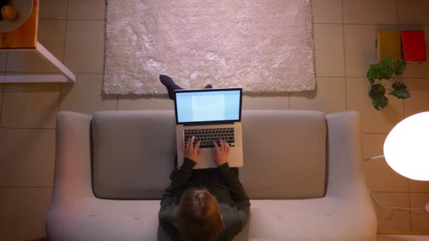 Närbild topp shoot av unga vackra affärskvinna skriva på den bärbara datorn medan du sitter på soffan inomhus på Cozy Home — Stockvideo