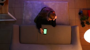 Rahat bir dairede kapalı yerde otururken yeşil ekran ile telefon kullanarak Tv izlerken güzel kadın genç Closeup üst ateş