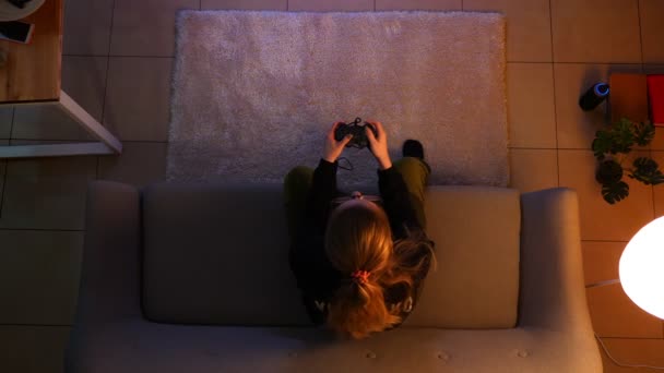 Close-up top shoot van mooie vrouwelijke spelen video games terwijl zittend op de Bank binnenshuis in een gezellig appartement met verlichting uit — Stockvideo