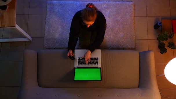 Close-up top shoot van mooie vrouw met behulp van de laptop terwijl zittend op het tapijt binnenshuis in een gezellig appartement — Stockvideo