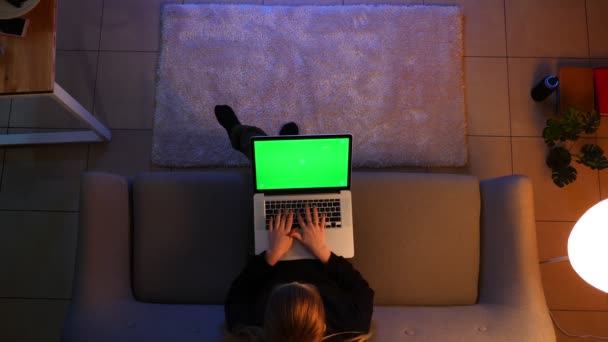 Closeup top shoot of pretty female using the laptop with green screen while sitting on the sofa indoors in a cozy apartment — Stock Video