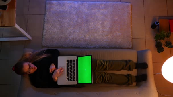 Closeup Top lő csinos női gépelés a laptop zöld képernyőt, miközben fekszik a kanapén beltéri egy hangulatos lakásban — Stock videók