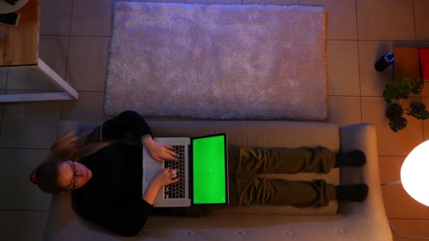 Gambar close-up top dari perempuan cantik SMS di laptop dengan layar hijau saat berbaring di sofa di dalam ruangan di apartemen yang nyaman — Stok Video