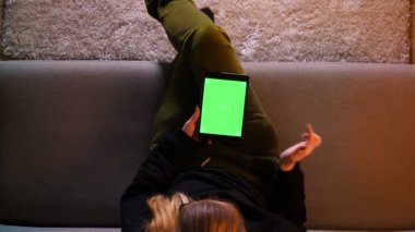Rahat bir dairede kanepede otururken yeşil ekran ile tablette sohbet güzel kız Closeup üst ateş
