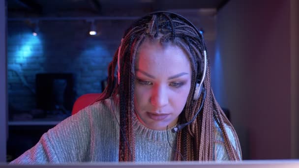 Gros plan shoot of young attractive female vlogger with dreadlocks playing video games and streaming live with the neon background — Video