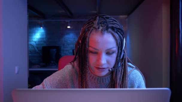 การถ่ายภาพใกล้ชิดของบล็อกเกอร์หญิงสาวที่น่าสนใจที่มี Dreadlocks ในหูฟังเล่นวิดีโอเกมที่มีพื้นหลังนีออน — วีดีโอสต็อก