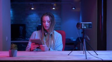 Tableti kullanarak canlı yayın ve neon arka plan kapalı kameraya yeşil renk ekran gösteren dreadlocks ile genç çekici kadın blogger Closeup ateş
