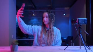 Dreadlocks cep telefonu neon arka plan kapalı canlı akışı selfie çekerek genç çekici kadın blogger Closeup ateş