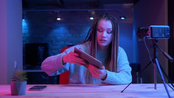 Closeup lő fiatal vonzó női blogger a raszta videojátékok a tabletta élőben a neon háttérben beltéri — Stock videók